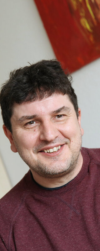 Klaus Henner Spierling im Gespräch mit einer anderen Person. Er schaut sie freundlich an, die andere Person ist von hinten zu sehen.