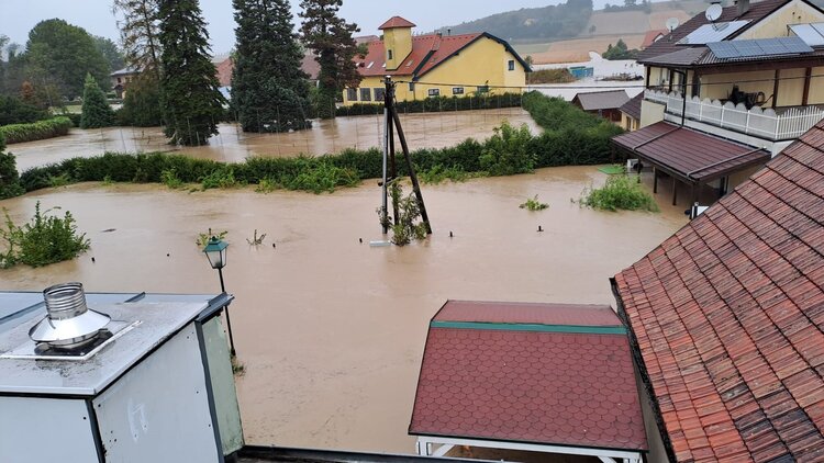 Eine Straße steht unter Wasser, einige Häuser schauen nur zum Teil aus dem Wasser hervor.