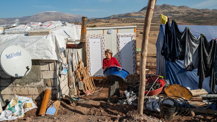 Eine Frau sitzt zwischen Zelten in einem Lager für Geflüchtete